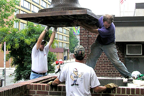Sculptor James Peniston, right, guides the sculpture into place. 'Keys To Community,' a nine-foot bronze bust of Ben Franklin for downtown Philadelphia